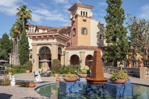 A Mediterranean-style building with a pool, palm trees, and a fountain. - 2-bedroom hotel suites with AC in enchanting Newport Beach (Newport Beach)