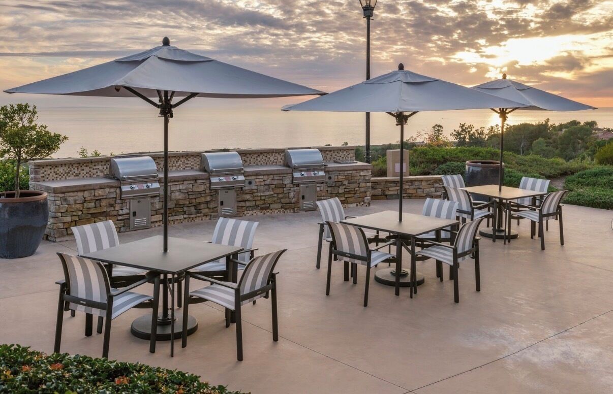 An outdoor patio with a stone wall, grill, and seating area.