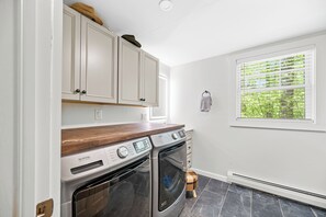 A laundry room with two Maytag dryers, a wooden countertop, and a window with blinds. - TreeTop Chalet 4BR & Pool - Upper Mtn Road Stowe (Stowe)