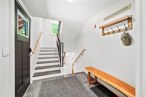 A staircase with a wooden handrail, a bench, a coat rack with a hat, and a welcome sign. - TreeTop Chalet 4BR & Pool - Upper Mtn Road Stowe (Stowe)