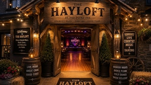 The entrance to The Hayloft at The Point Inn, featuring a rustic wooden facade, a welcoming sign, and a path leading to the interior.