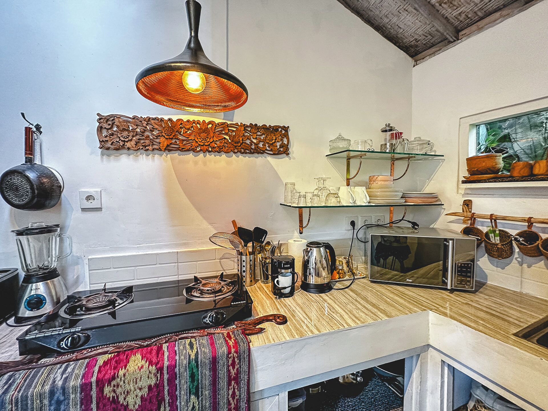 Una cocina con estufa a gas, licuadora, hervidor y microondas sobre la encimera.