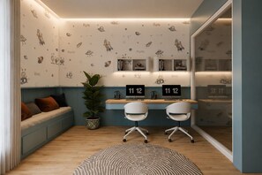 Ein Zimmer mit blauer Wand, einer Sitzecke mit Pflanze und einem Schreibtisch mit zwei Stühlen.