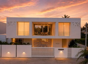 A modern two-story building with large windows, a balcony, and a gated entrance. - BRAND NEW The Palm Reserve Luxury Beach Villa Thailand (4 bedrooms/ 5 bathrooms) (Pak Nam Pran)