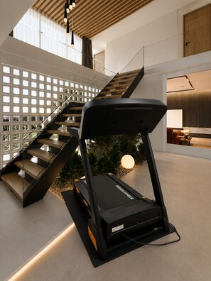 Ein modernes Interieur mit einer Treppe, einem Laufband und einer Wand mit Rasteroptik.