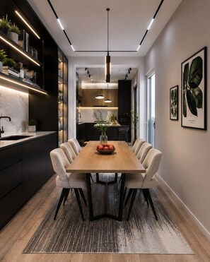 A modern dining area with a wooden table, six chairs, a vase with flowers, and a kitchen in the background. - BRAND NEW The Palm Reserve Luxury Beach Villa Thailand (4 bedrooms/ 5 bathrooms) (Pak Nam Pran)