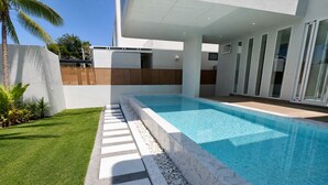 A modern outdoor swimming pool with a clear blue water surface, surrounded by a well-maintained lawn and a stone pathway leading to the pool. - BRAND NEW The Palm Reserve Luxury Beach Villa Thailand (4 bedrooms/ 5 bathrooms) (Pak Nam Pran)