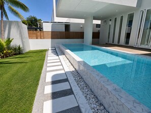 A modern outdoor swimming pool with a clear blue water surface, surrounded by a well-maintained lawn and a stone pathway leading to the pool. - BRAND NEW The Palm Reserve Luxury Beach Villa Thailand (4 bedrooms/ 5 bathrooms) (Pak Nam Pran)