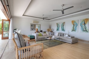 A modern living room with a sofa, coffee table, and a ceiling fan. - Villa Bayu Uluwatu (denpasar)
