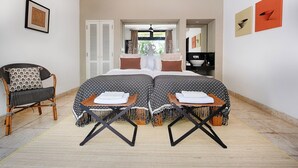 A bedroom with a bed, two side tables, a chair, and a bathroom visible through an open door. - Villa Bayu Uluwatu (denpasar)