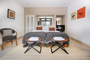A bedroom with a bed, two side tables, a chair, and a bathroom visible through an open door. - Villa Bayu Uluwatu (denpasar)