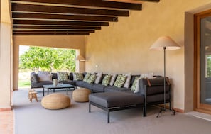 Ein modernes Wohnzimmer mit einem Ecksofa, zwei Poufs, einem Couchtisch und einer Stehlampe.