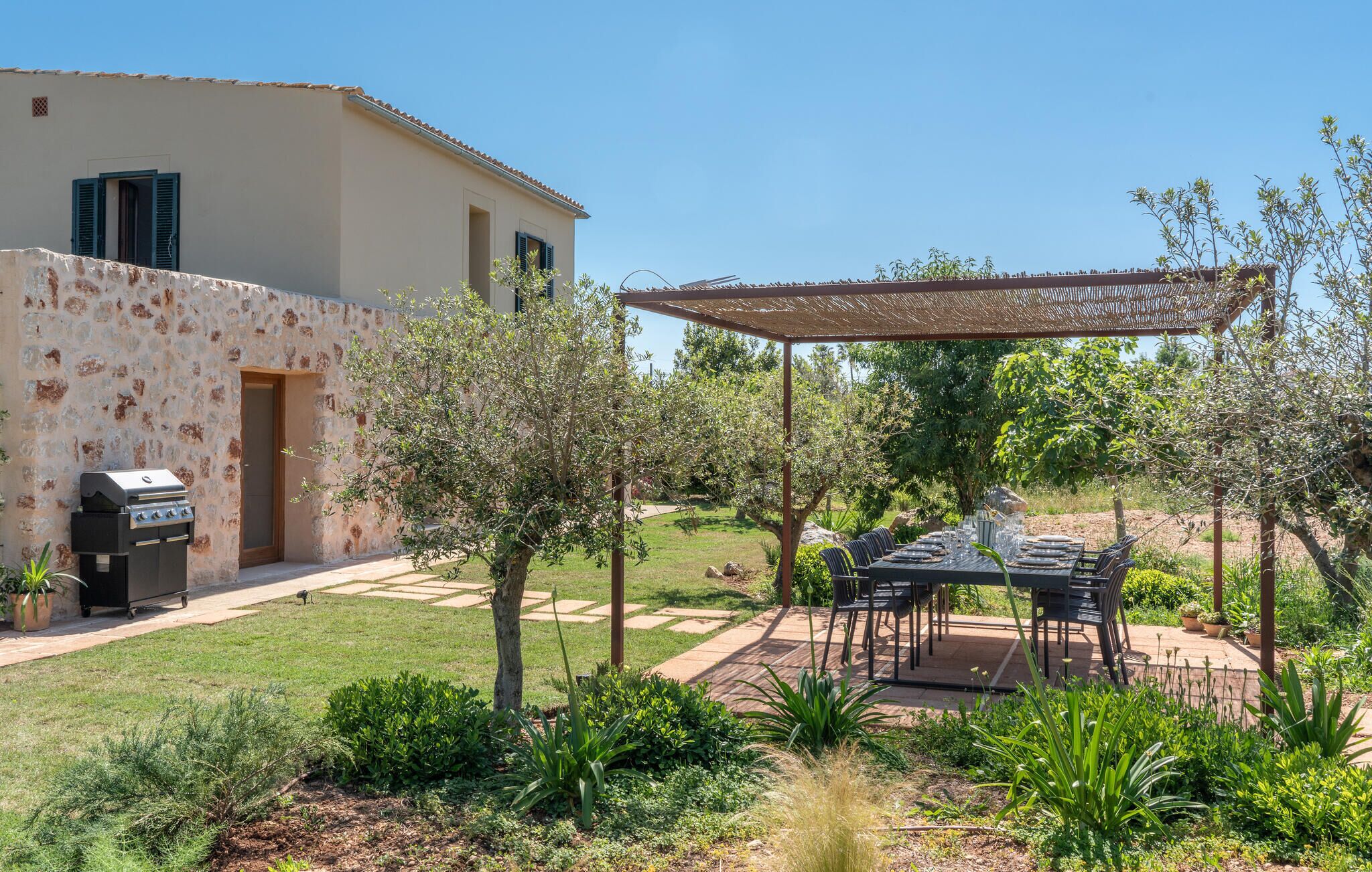 A patio with a grill, outdoor furniture, and a pergola.