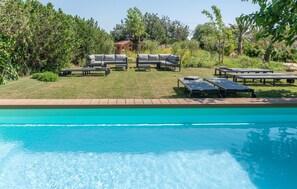 Ein Schwimmbecken mit Liegestühlen und einem Gebäude im Hintergrund.