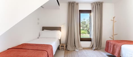 A bedroom with two beds, a window with curtains, a small stool, and a wooden coat rack.