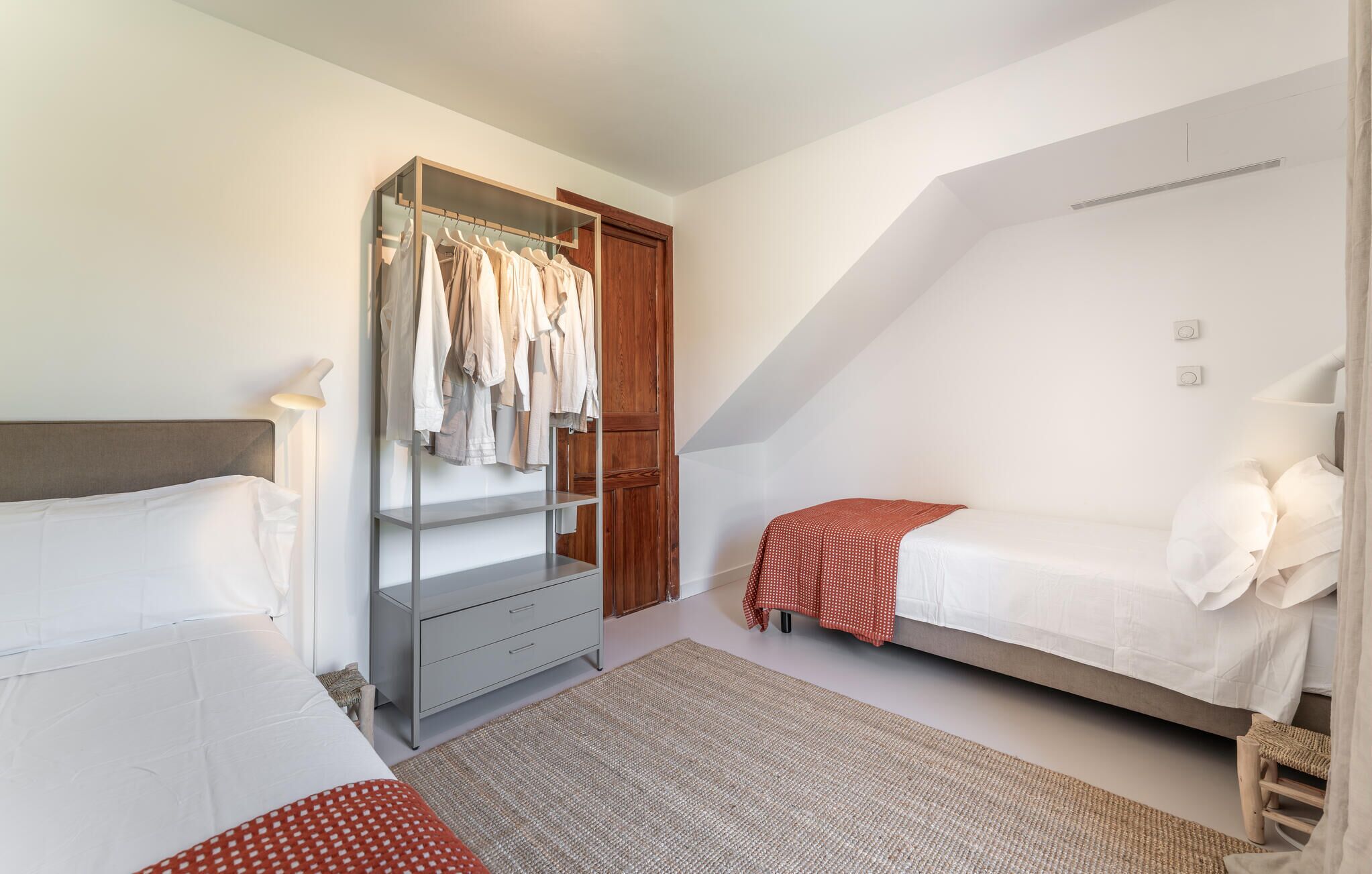 A bedroom with a bed, a wardrobe, a desk, and a small seating area.