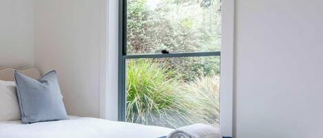 A single bed with a white headboard, a dark blue blanket, and a white pillow.