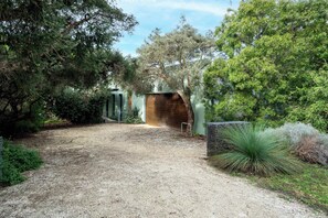 A gravel driveway leading to a modern building with a wooden door and a metal gate. - Coastal Elegance in Old Point Lonsdale  Pet Friendly (Point Lonsdale)