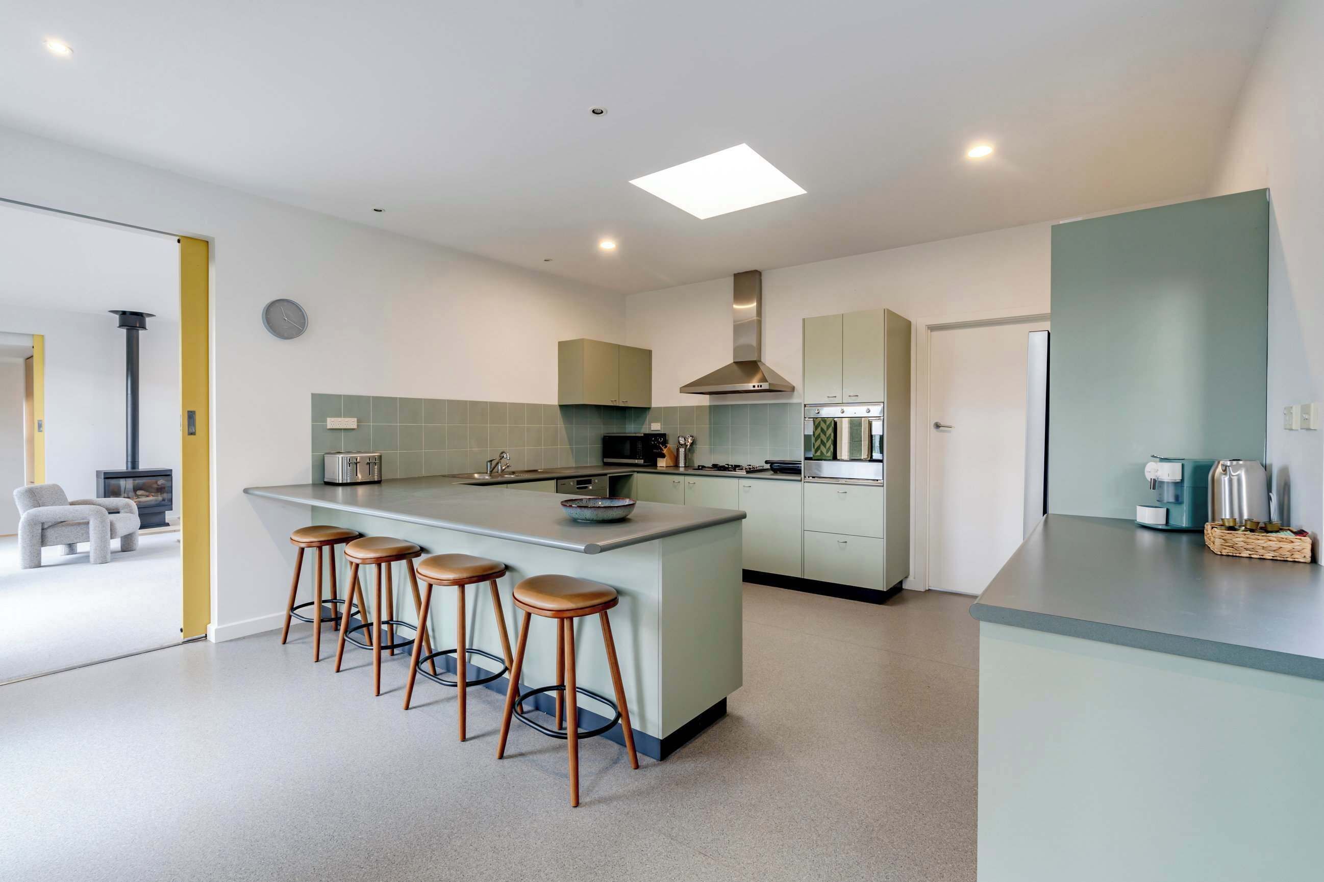 A modern kitchen with a central island, bar stools, and a built-in oven.