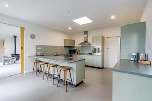 A modern kitchen with a central island, bar stools, and a built-in oven. - Coastal Elegance in Old Point Lonsdale  Pet Friendly (Point Lonsdale)