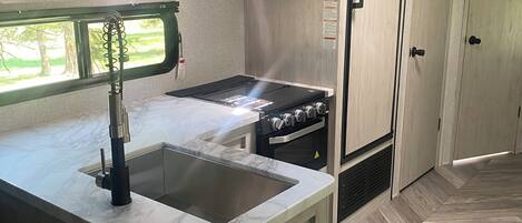 Una cocina compacta con microondas integrado, estufa y pileta.