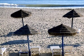 Ein Strand mit Strohdächern und weißen Liegestühlen.