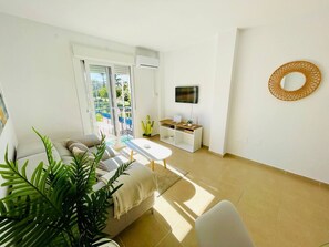 Ein modernes Wohnzimmer mit einer Couch, einem Couchtisch und einem Fernseher auf einem Lowboard.
