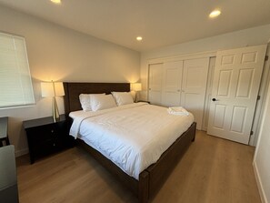 Un dormitorio con cama, mesitas de noche, lámpara, armario y puerta.