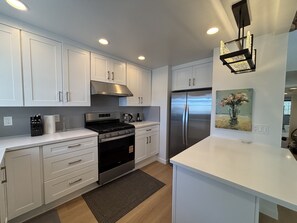 Una cocina moderna con armarios blancos, electrodomésticos de acero inoxidable e iluminación empotrada.