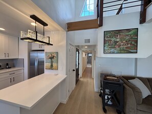 A modern kitchen with a large island, stainless steel appliances, and a pendant light fixture.