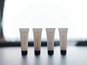Quatre tubes de produits de soins pour la peau, étiquetés « SHOLAYERED FRESH PEAR », sont posés sur une table.