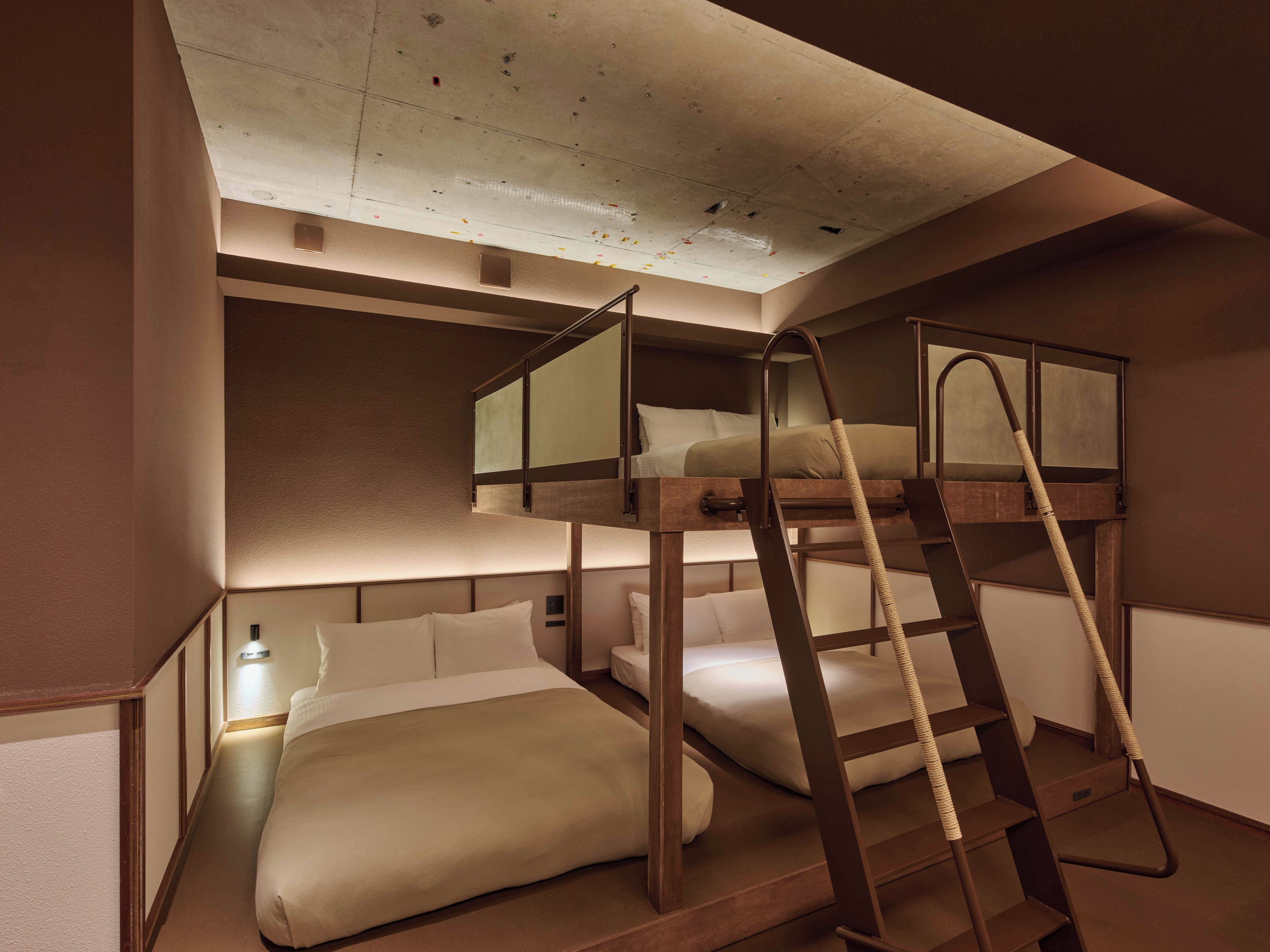 Habitación con literas, una mesita de noche y una lámpara fijada a la pared.