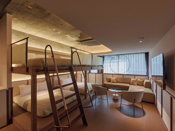 Une chambre d’hôtel moderne équipée de lits superposés, d’un canapé, d’une petite table et d’un téléviseur.