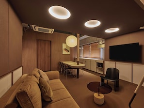 Una sala de estar moderna con un sofá, una mesa de comedor y un televisor montado en la pared.