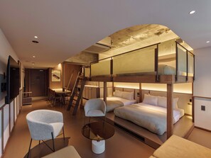 Una habitación de hotel moderna con literas, una zona de comedor y una escalera.