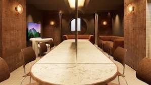 Uma sala de conferências com uma mesa comprida, cadeiras e uma tela de televisão.