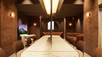 A conference room with a long table, chairs, and a TV screen.