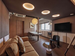 Un salon moderne avec un canapé, une table à manger et un téléviseur fixé au mur.