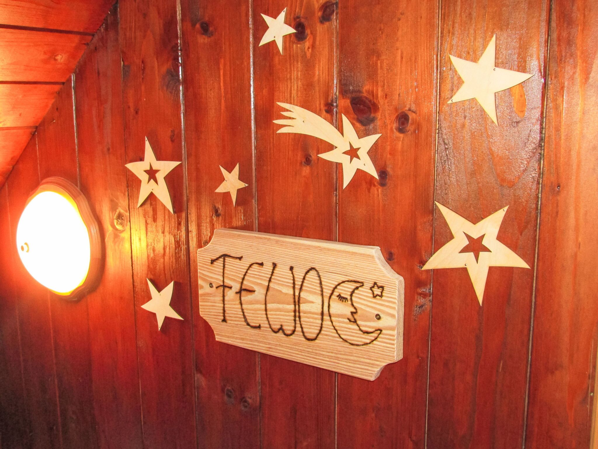 A wooden wall with star decorations and a sign that reads 'FEWOC'.