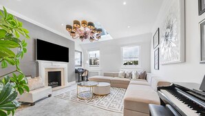 A modern living room with a fireplace, sofa, coffee table, and a grand piano. - Urban Escape 2 Bedroom Apartment Near Hyde Park (London)