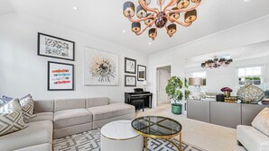 A modern living room with a sectional sofa, a glass coffee table, and artwork on the walls. - Urban Escape 2 Bedroom Apartment Near Hyde Park (London)