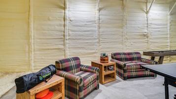 A room with a pool table, two plaid sofas, a small wooden table with a bag and a remote control, and a wall with a textured finish.