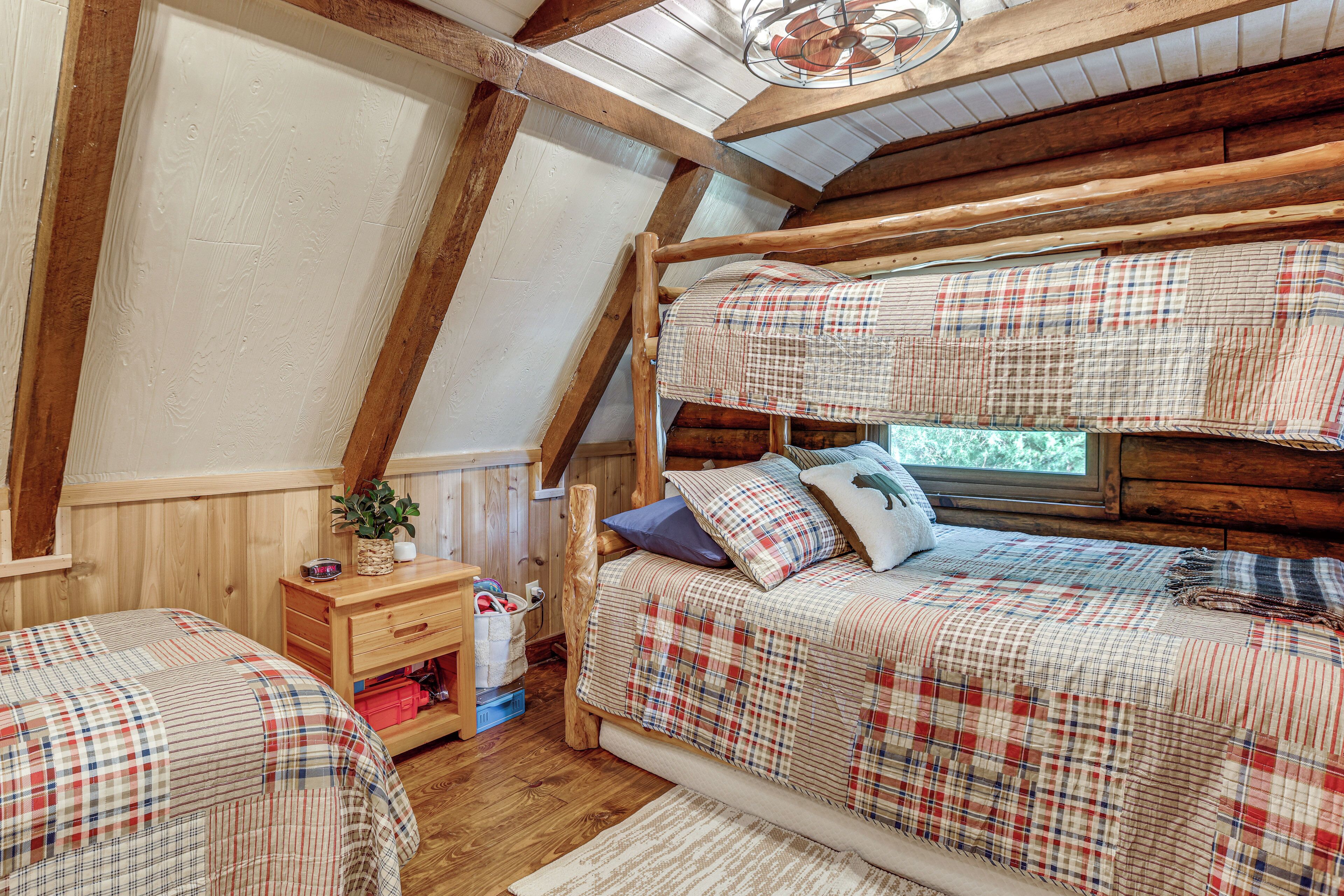 Une chambre mansardée chaleureuse, avec un plafond en pente, des poutres en bois et un lit superposé doté de draps à carreaux.