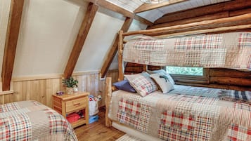 A cozy attic bedroom with a sloped ceiling, wooden beams, and a bunk bed with plaid bedding.