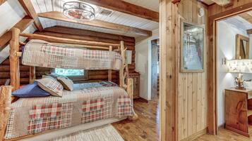A log cabin bedroom with a bunk bed, wooden walls, and a rustic aesthetic.