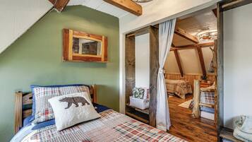 A cozy bedroom with a bed, a wooden headboard, a green wall, a wooden ceiling, and a window with curtains.