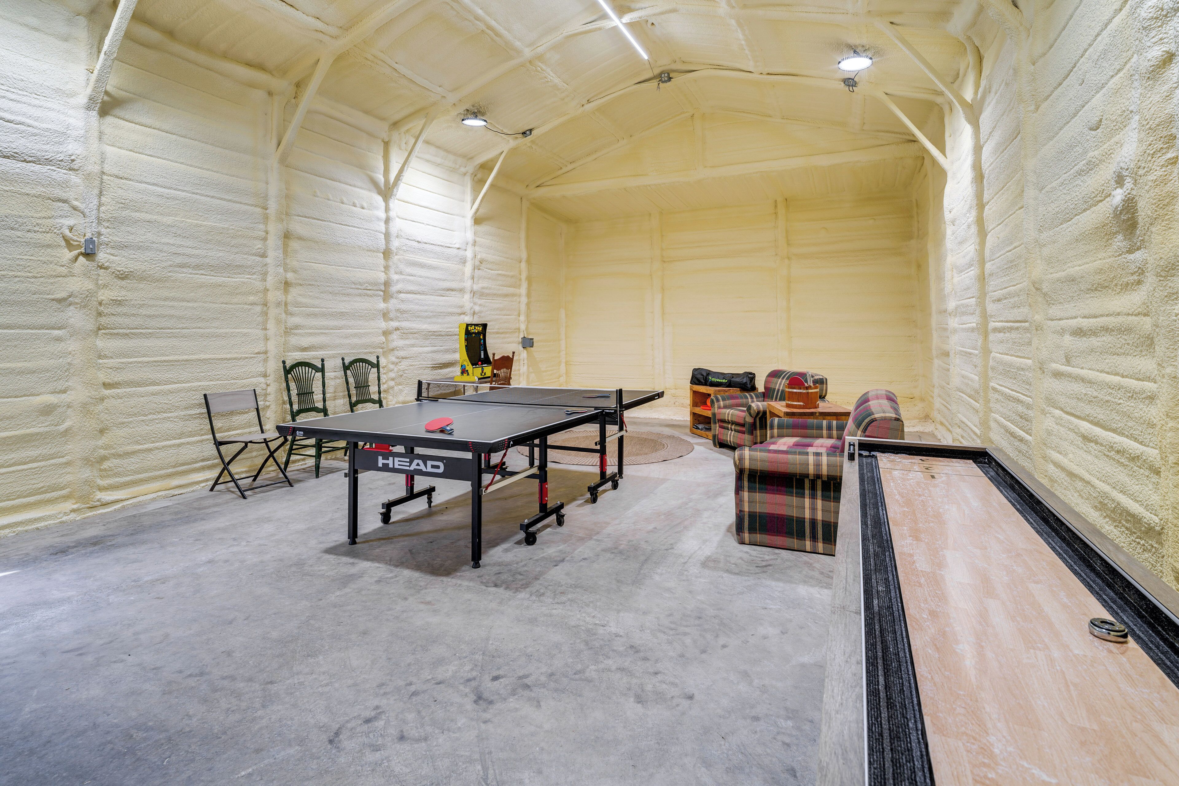 Una mesa de ping pong en una habitación con techos altos y paredes aisladas.
