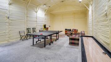 Una mesa de ping pong en una habitación con techos altos y paredes aisladas.