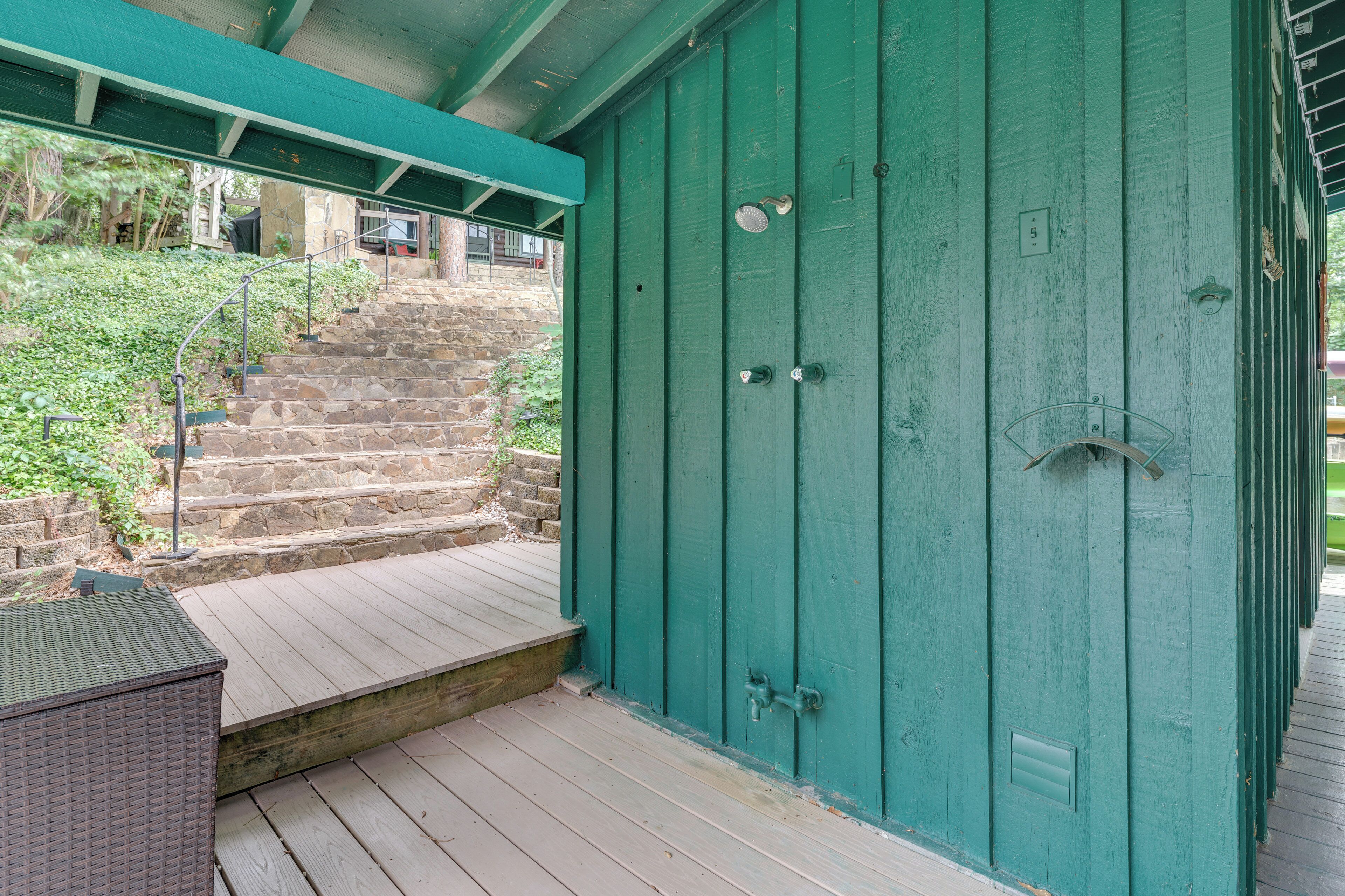 Une porte verte avec une poignée en métal, un escalier en pierre et une rampe en métal.