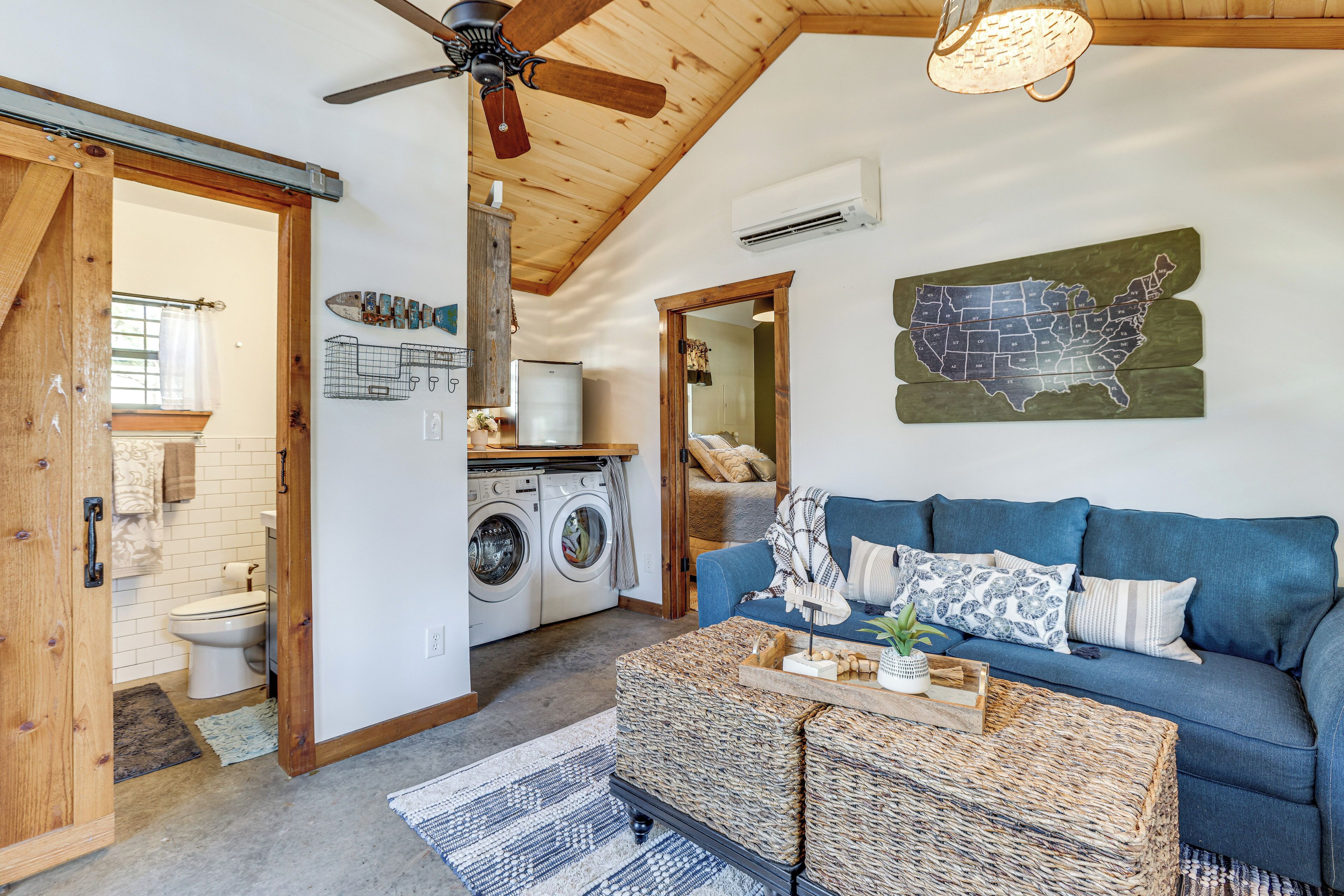 A cozy living room with a blue sofa, a wicker coffee table, and a map of the USA on the wall.
